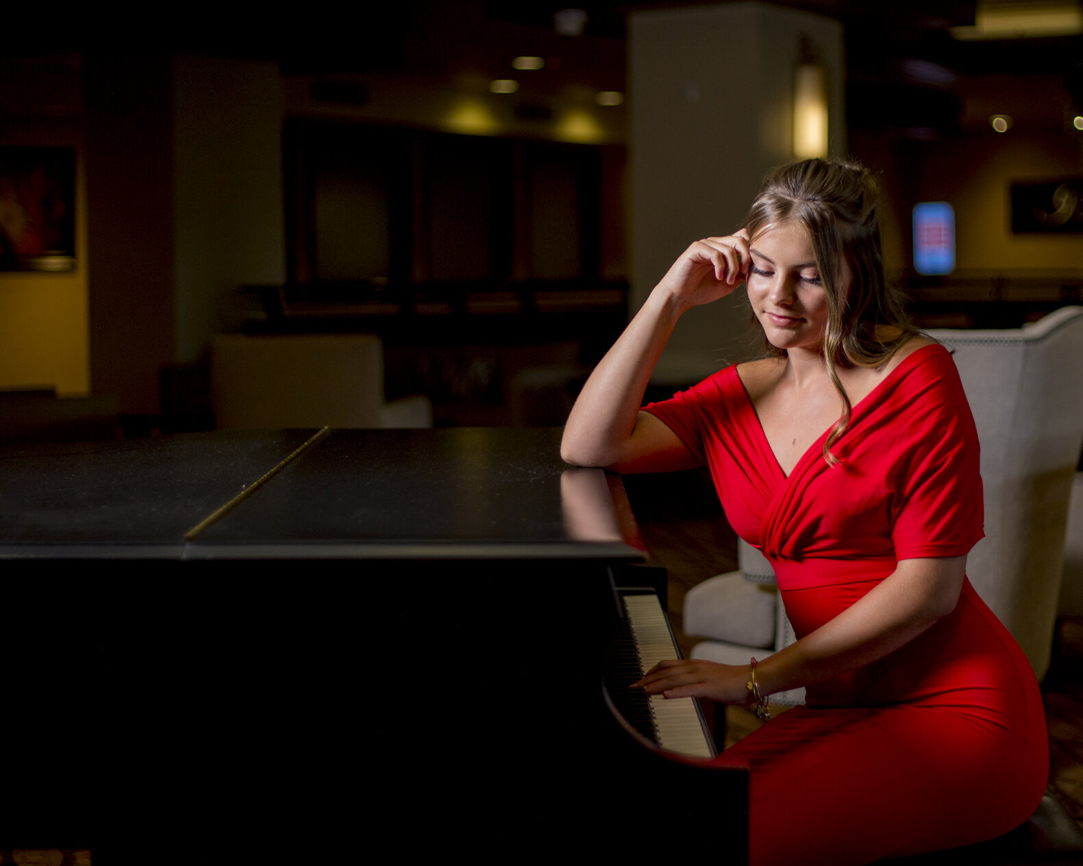 A high school senior girl plays the piano for her high school senior photography session.