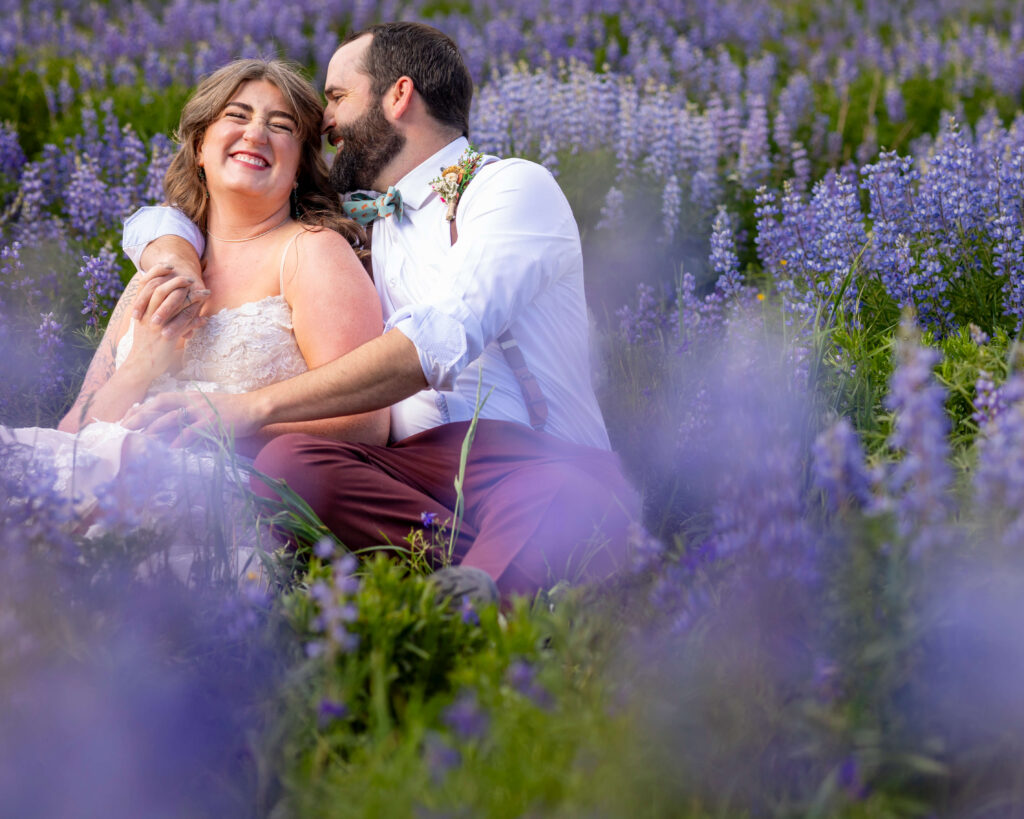 Joyful couple embracing in a field of purple lavender under a sunny sky.
